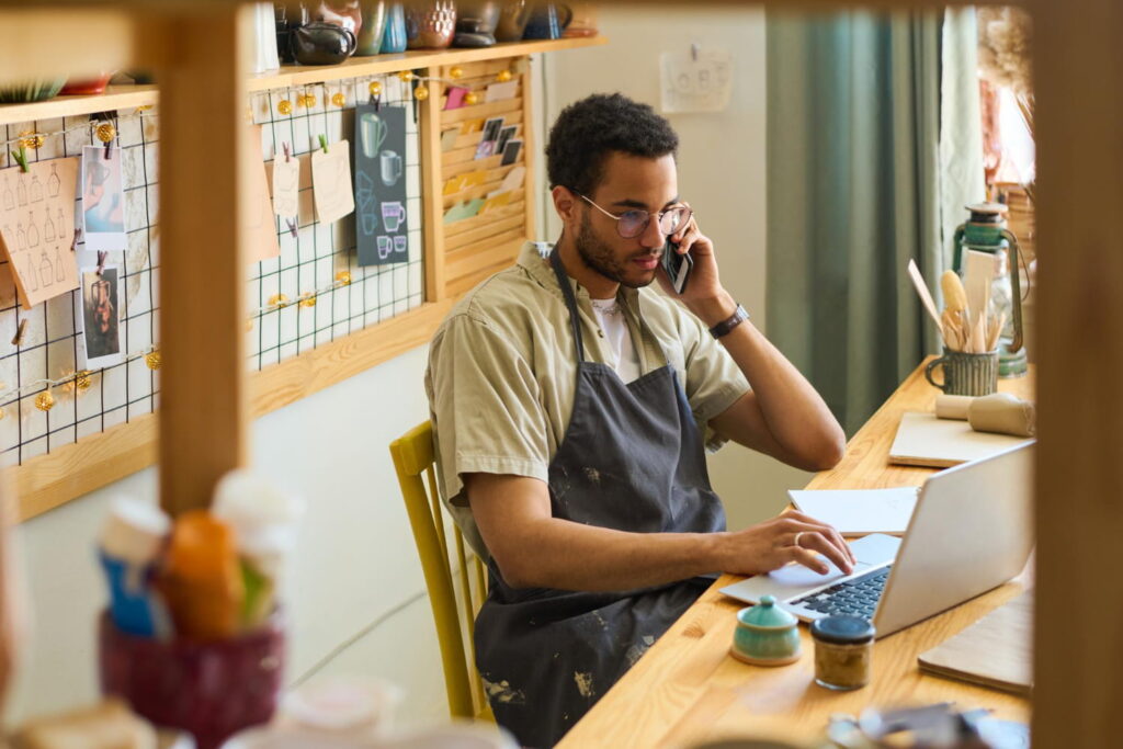 small business owner doing work on laptop while talking on mobile