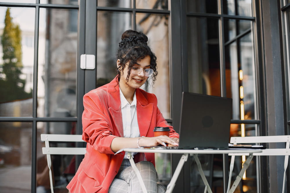 a girl working on website citation laptop in a road side cafe